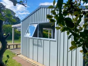 a small house with a window on the side of it at Beach Break Cabin - short walk to beach and cafes in Waihi Beach