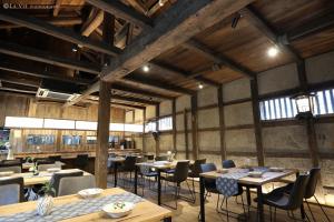 una sala da pranzo con tavoli, sedie e finestre di NIPPONIA HARIMA FUKUSAKI ZOUSHONO YAKATA a Fukusaki