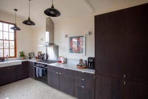 a kitchen with dark brown cabinets and a stove at Rochville - Luxe, Dog Friendly Townhouse, Kyneton in Kyneton