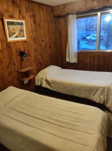 a hotel room with two beds and a window at Hotel Panoramico Bariloche in San Carlos de Bariloche