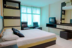 a bedroom with a bed and a tv and chairs at Hotel Sampurna Jaya in Tanjung Pinang 