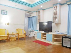 a living room with a flat screen tv and chairs at Hua Ku Hotel in Tainan