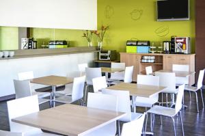 a restaurant with white tables and white chairs at ibis Budget Sydney Olympic Park in Sydney