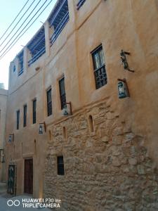 an old stone building with windows on the side of it at Bait Baityn بيت البيتين in Misfāh