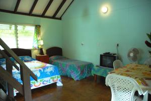 a bedroom with two beds and a tv in it at Ginas Garden Lodges, Aitutaki - 4 self contained lodges in a beautiful garden in Arutanga