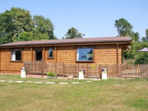 a wooden cabin with a fence in front of it at South Lodge in Great Moulton