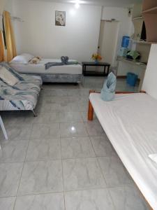 Habitación con 3 camas y suelo de baldosa. en Okoy Guest House, en Bantayan Island