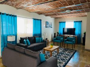 - un salon avec des rideaux bleus, un canapé et une télévision dans l'établissement Finca Ybarra, casa de campo, à Chapala