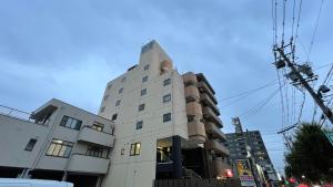 un edificio blanco con una torre encima en HOTEL THE GARDEN Ⅵ ICHINOMIYA en Ichinomiya