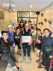 a group of people posing for a picture with a sign at Doze Hostel in Chiang Mai