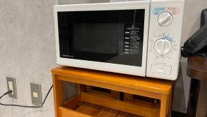 a microwave oven sitting on top of a wooden stand at HOTEL THE GARDEN Ⅵ ICHINOMIYA in Ichinomiya