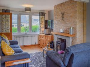 a living room with two blue couches and a fireplace at Burnside Cottage in Bruichladdich