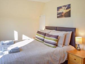 a bedroom with a bed with pillows on it at Burnside Cottage in Bruichladdich