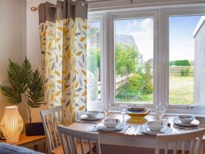 a dining room table with chairs and a window at Burnside Cottage in Bruichladdich