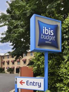 a blue and white sign on a pole in front of a building at ibis Budget Brisbane Airport in Brisbane