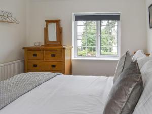 sypialnia z łóżkiem z lustrem i komodą w obiekcie Old Road Cottage w mieście Conwy