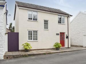 una casa blanca con una puerta roja y dos macetas en Old Road Cottage, en Conwy