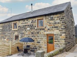 a stone cottage with a table and chairs and an umbrella at 2 The Calf Pens in Stannington