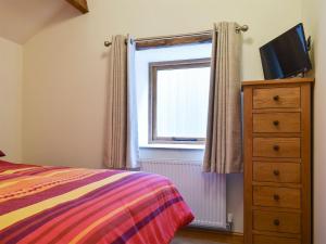 a bedroom with a bed and a dresser and a window at 2 The Calf Pens in Stannington