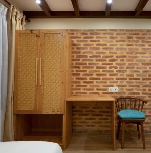 1 dormitorio con escritorio, silla y pared de ladrillo en Karuna Hotel Patan Kathmandu, en Pātan
