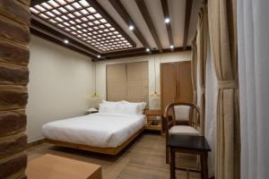 帕坦Karuna Hotel Patan Kathmandu的一间带床和椅子的酒店房间