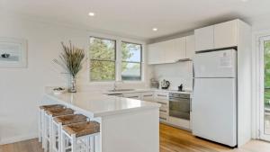 a kitchen with white cabinets and a white refrigerator at 55 The Boulevarde Hawks Nest in Hawks Nest