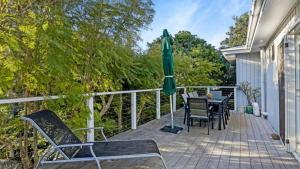 a deck with a table and chairs and an umbrella at 55 The Boulevarde Hawks Nest in Hawks Nest