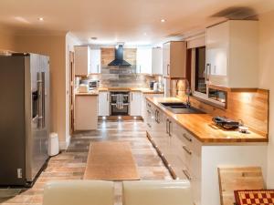 a large kitchen with white cabinets and wooden counter tops at Hilbre in Strachur