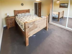 sypialnia z drewnianym łóżkiem i lustrem w obiekcie Hilbre w mieście Strachur
