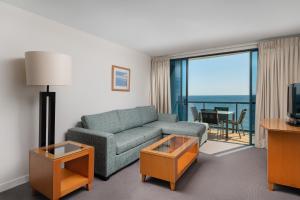 a living room with a couch and a view of the ocean at Mantra Mooloolaba Beach in Mooloolaba