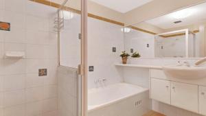 a white bathroom with a tub and a sink at 1 Aquarius 9 Beach Rd Hawks Nest in Hawks Nest