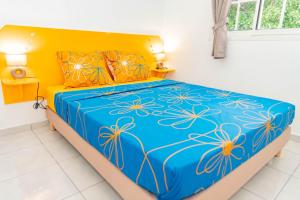 - une chambre dotée d'un lit bleu et jaune avec des oreillers orange dans l'établissement Les paisibles villas C & G, à Richeplaine