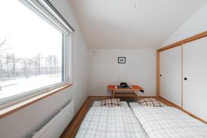 two beds in a room with a window at 6ty6 Vacation Home in Niseko