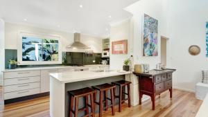 a kitchen with white cabinets and a island with bar stools at The Blue Beach House in Hawks Nest