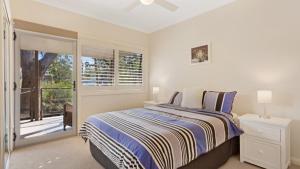 a white bedroom with a bed and a window at Binda Beauty in Hawks Nest