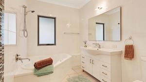 a white bathroom with a tub sink and a mirror at Binda Beauty in Hawks Nest
