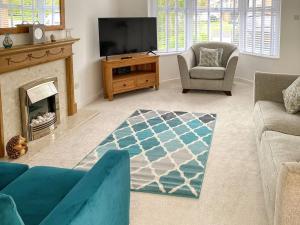 a living room with a tv and a couch and a fireplace at Paradise House in Honington