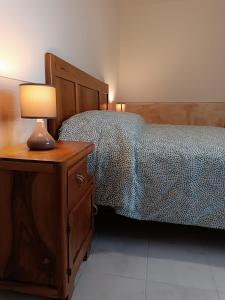 Dormitorio con cama y mesita de noche con lámpara en Casetta nel Borgo Pianello con vista panoramica, en Muro Lucano