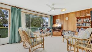 a living room with chairs and a book shelf at 4 Kururma Crescent Hawks Nest in Hawks Nest