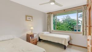 a bedroom with two beds and a window at 4 Kururma Crescent Hawks Nest in Hawks Nest