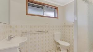 a bathroom with a toilet and a sink and a window at 4 Kururma Crescent Hawks Nest in Hawks Nest +3 photos
