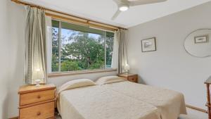 a bedroom with a bed and a large window at 4 Kururma Crescent Hawks Nest in Hawks Nest