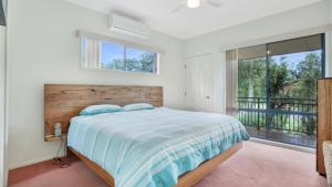 ein Schlafzimmer mit einem Bett und einem Balkon in der Unterkunft Sunset Cottage in Hawks Nest