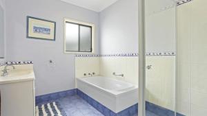 ein weißes Badezimmer mit Badewanne und Waschbecken in der Unterkunft Sunset Cottage in Hawks Nest
