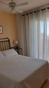 a bedroom with a white bed and a window at Ático con terraza abierta/Open terrace apartment in Mijas