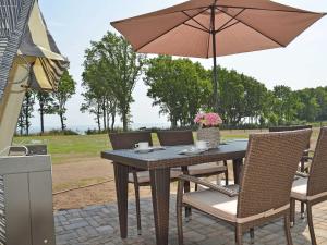 einen Tisch und Stühle mit Sonnenschirm auf einer Terrasse in der Unterkunft Reethus am Strand - Haushälfte 1 mit Kamin, Sauna in Lobbe