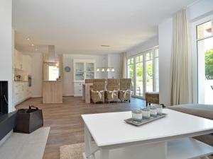 a living room with a white table and a kitchen at Reethus am Strand - Haushälfte 2 mit Kamin, Sauna in Lobbe