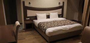 a bedroom with a large bed with a wooden headboard at City Palace Hotel in Ohrid