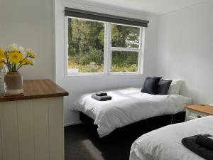 1 dormitorio con 2 camas y ventana en Superior Cottage - St Enoch and St Elijah Monastery, en Kaikohe