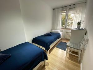 twee bedden in een kamer met een raam en een stoel bij Apartament Cynamon II in Sandomierz